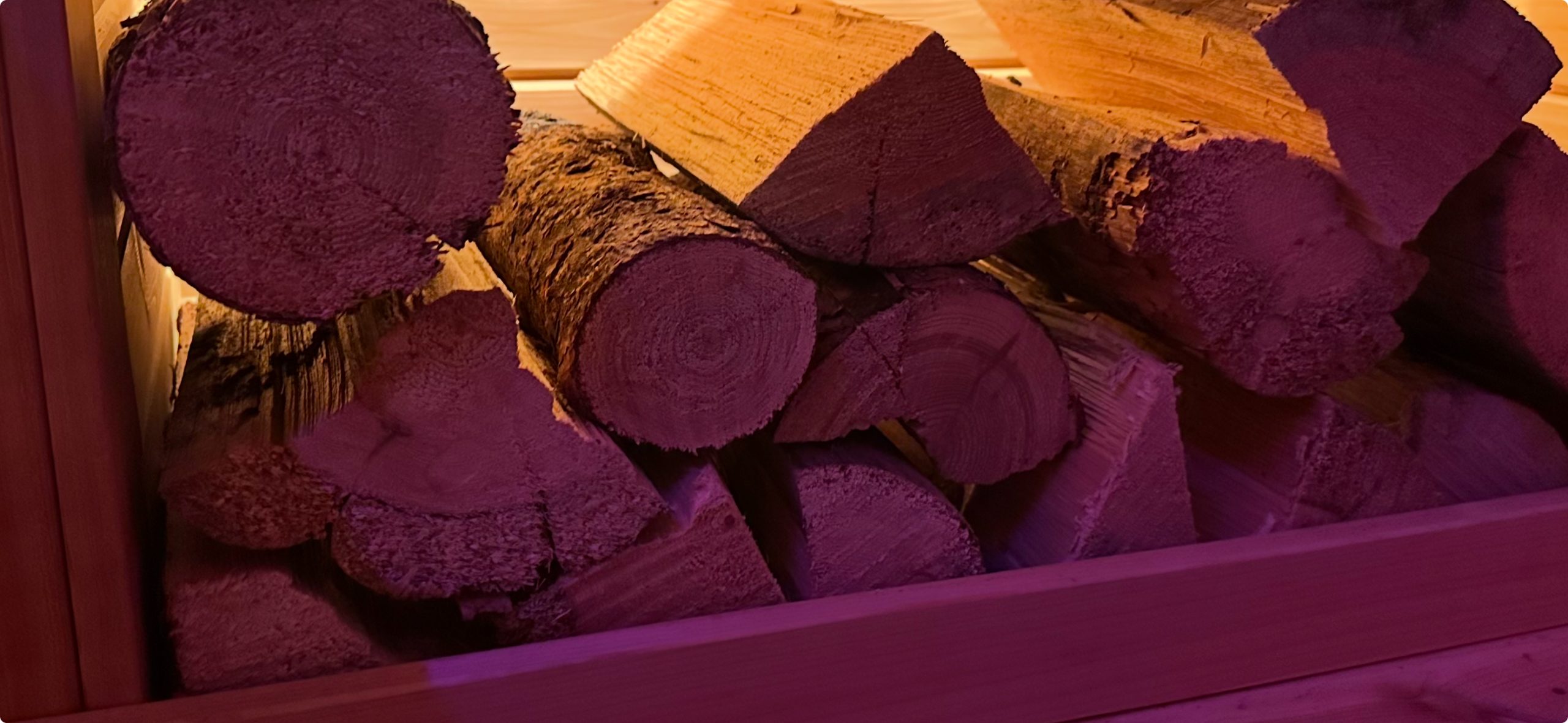 Firewood neatly stowed in a storage cubby inside Bliss Mobile Sauna’s cedar sauna, showcasing functionality and natural warmth for an authentic experience