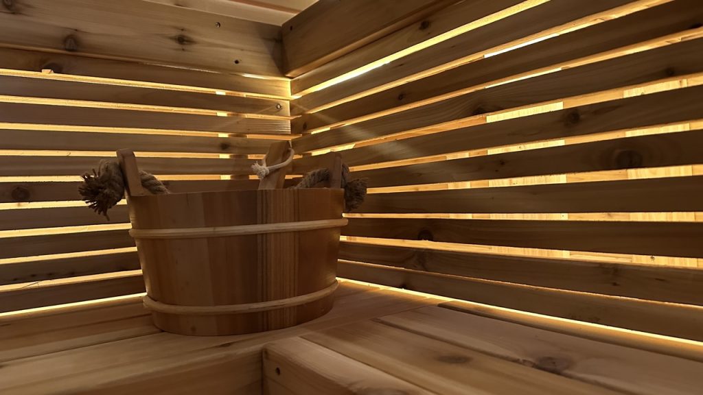 Traditional wooden sauna bucket and ladle on a cedar bench, perfect for enhancing steam sessions with water and aromatherapy