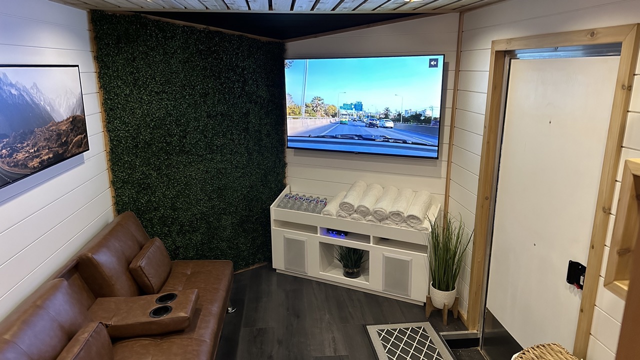 Modern Bliss Mobile Sauna lounge with leather seating and a scenic view of the cedar sauna setup