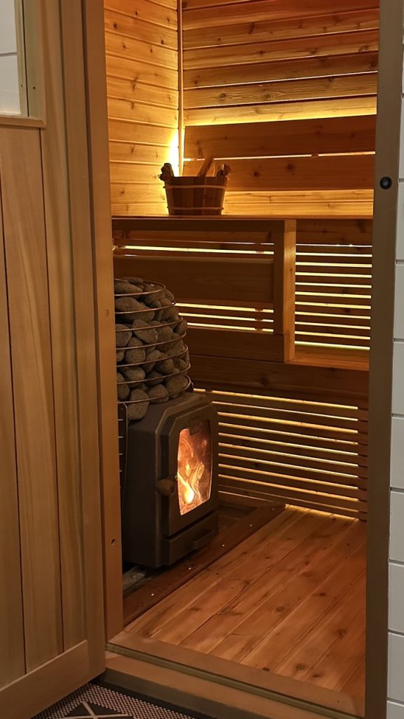 Close-up of Bliss Mobile Sauna’s wood-burning heater with smooth sauna stones, radiating heat and comfort