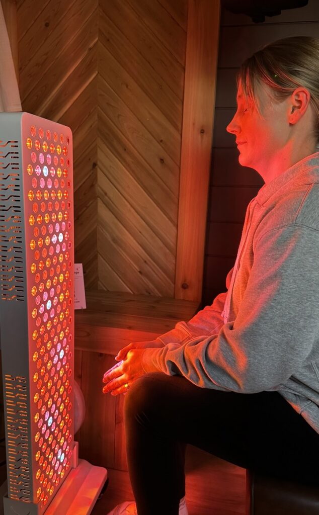 Red light therapy and mobile sauna guest under glow of red light therapy in between sauna session